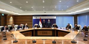 A group of people sitting around a table signing an agreement with the Egyptian flag in the background