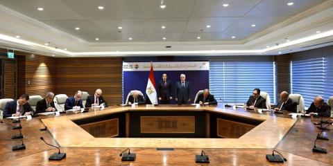 A group of people sitting around a table signing an agreement with the Egyptian flag in the background