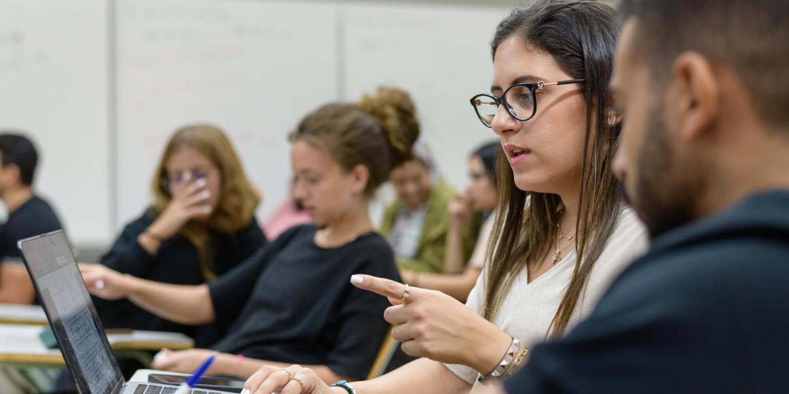 female student in class discussing project with team member