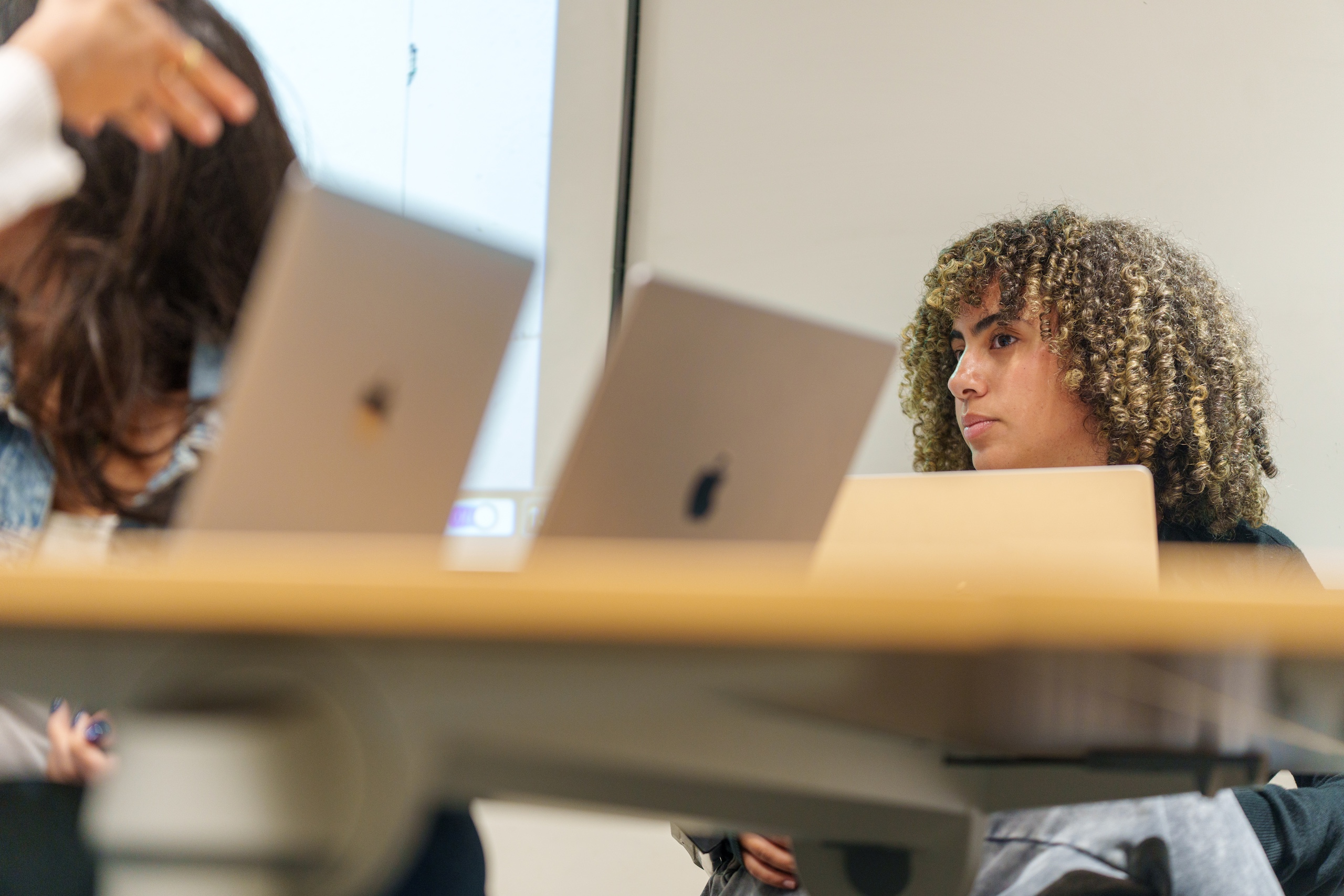 a student with short blond curly hair sitting in a classroom