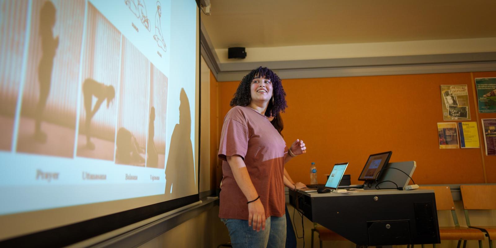 a girl with black curly hair giving a presentation in a classroom