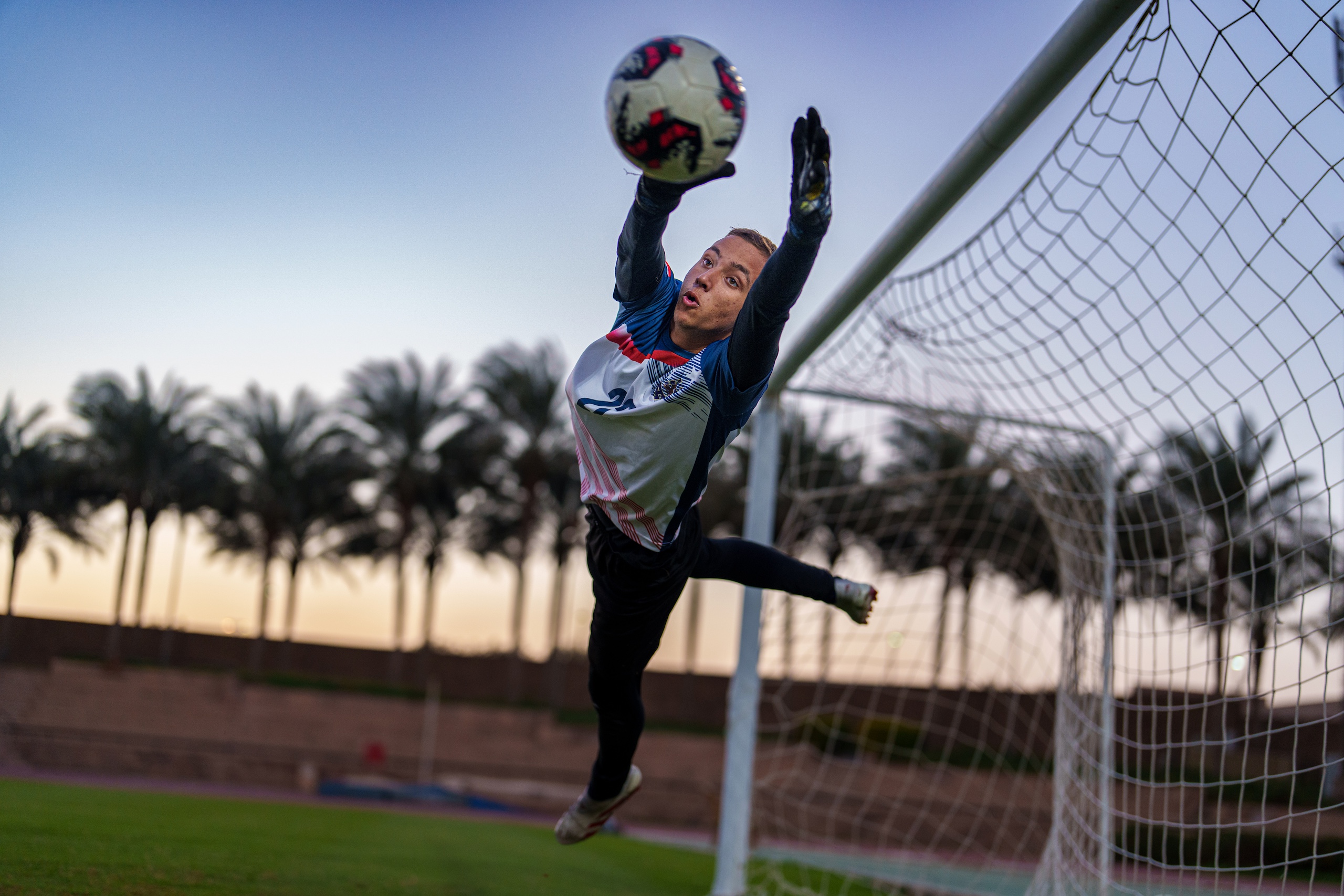 a goal keeper jumping to catch the ball