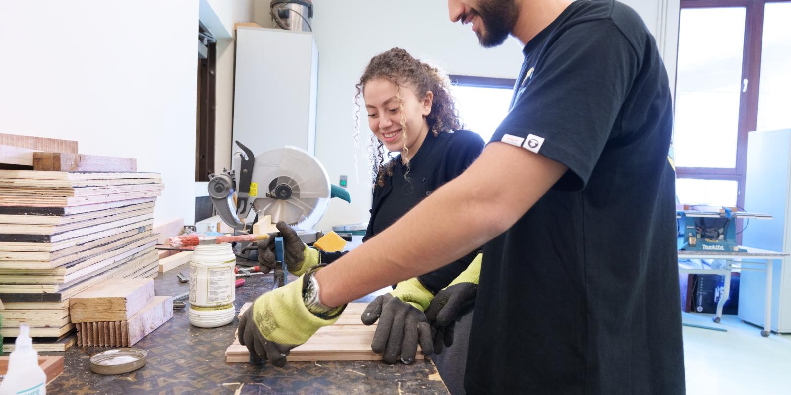 a girl and a boy wearing black tshirts working on an experiment in a lab