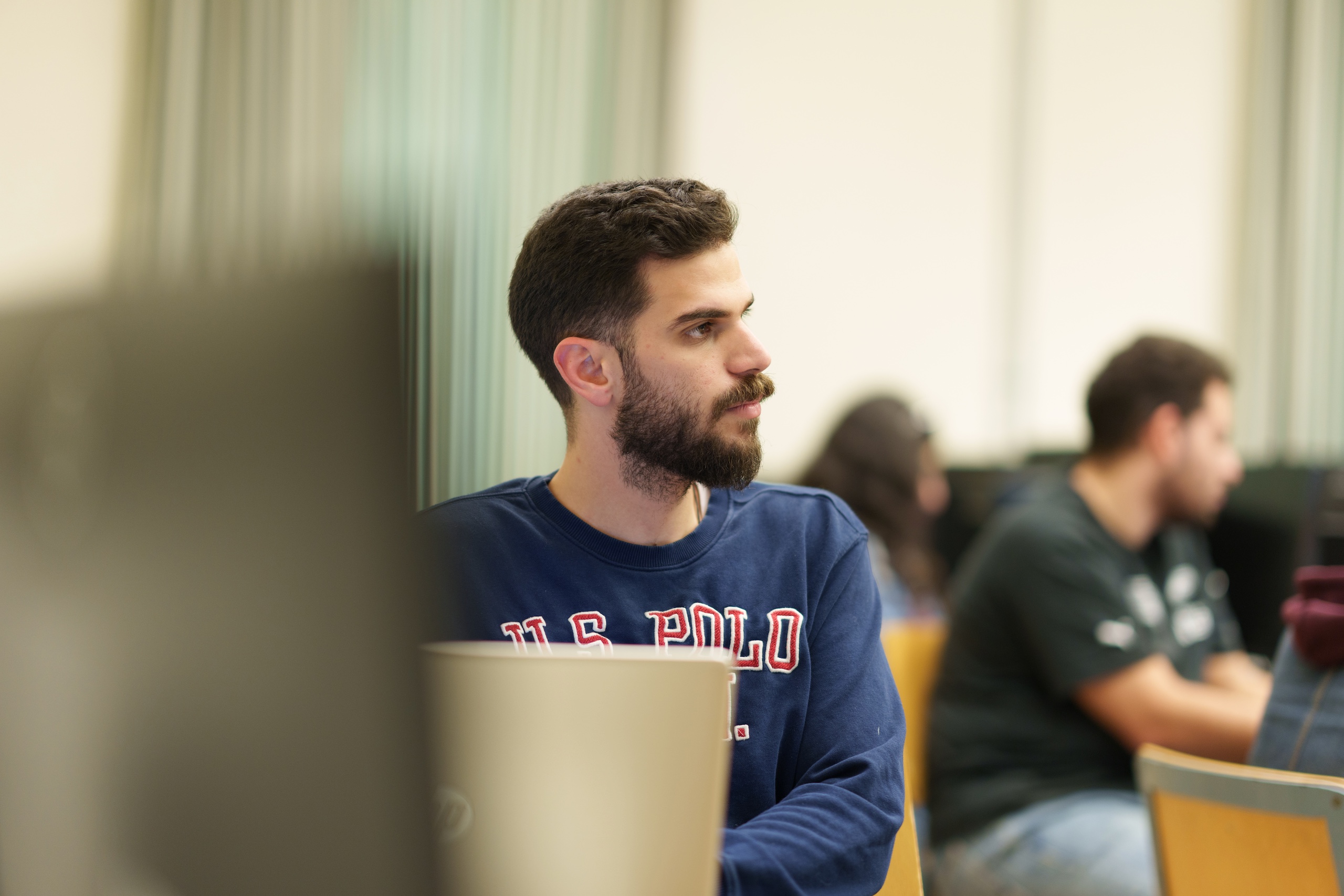 a student with long brown hair and long beard wearing a navy long sleeve tshirt