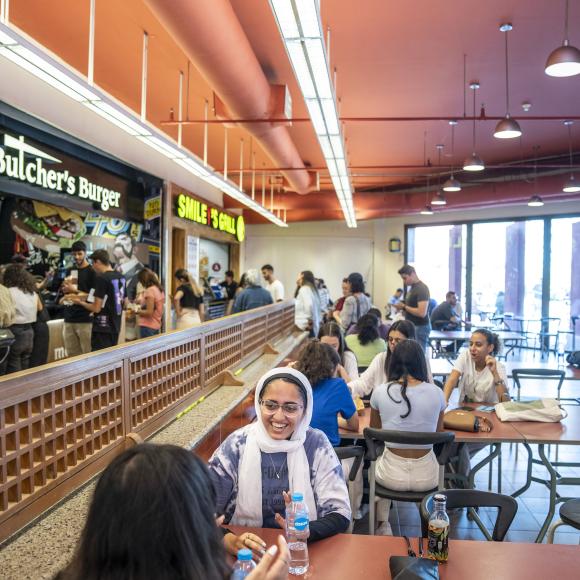 Students sitting on a food court with food vendors in the background