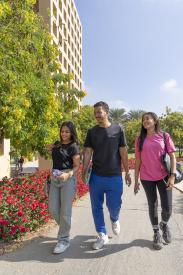 two girls and one boy walking together on campus and happily smiling