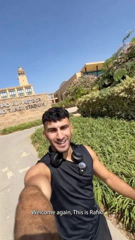 A male is walking in a garden and smiling. Text: Welcome again. This is Rafik. Al Habtoor. Track Stadium