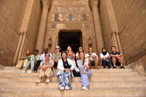 International students sitting on the stairs of an old mosque. They are smiling