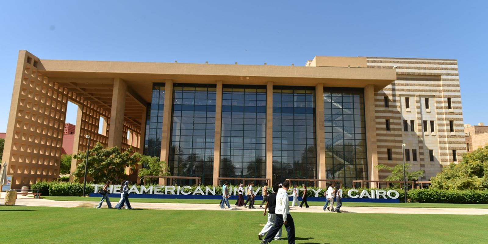 Students walking in front of a building. Text: The American University in Cairo