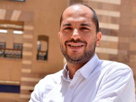 Man wearing a white shirt smiling with his hands crossed