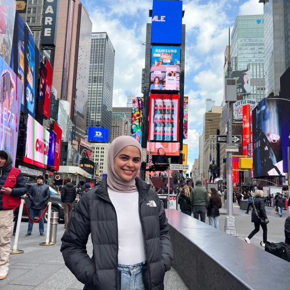 A female is standing in a street with lots of colored and light billboards