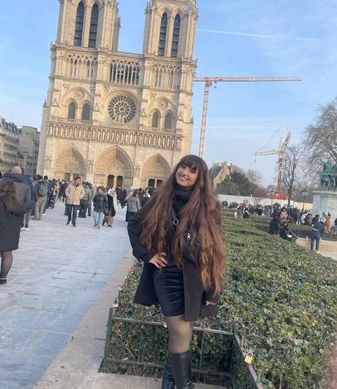 A female is standing in front of Notre Dame Cathedral