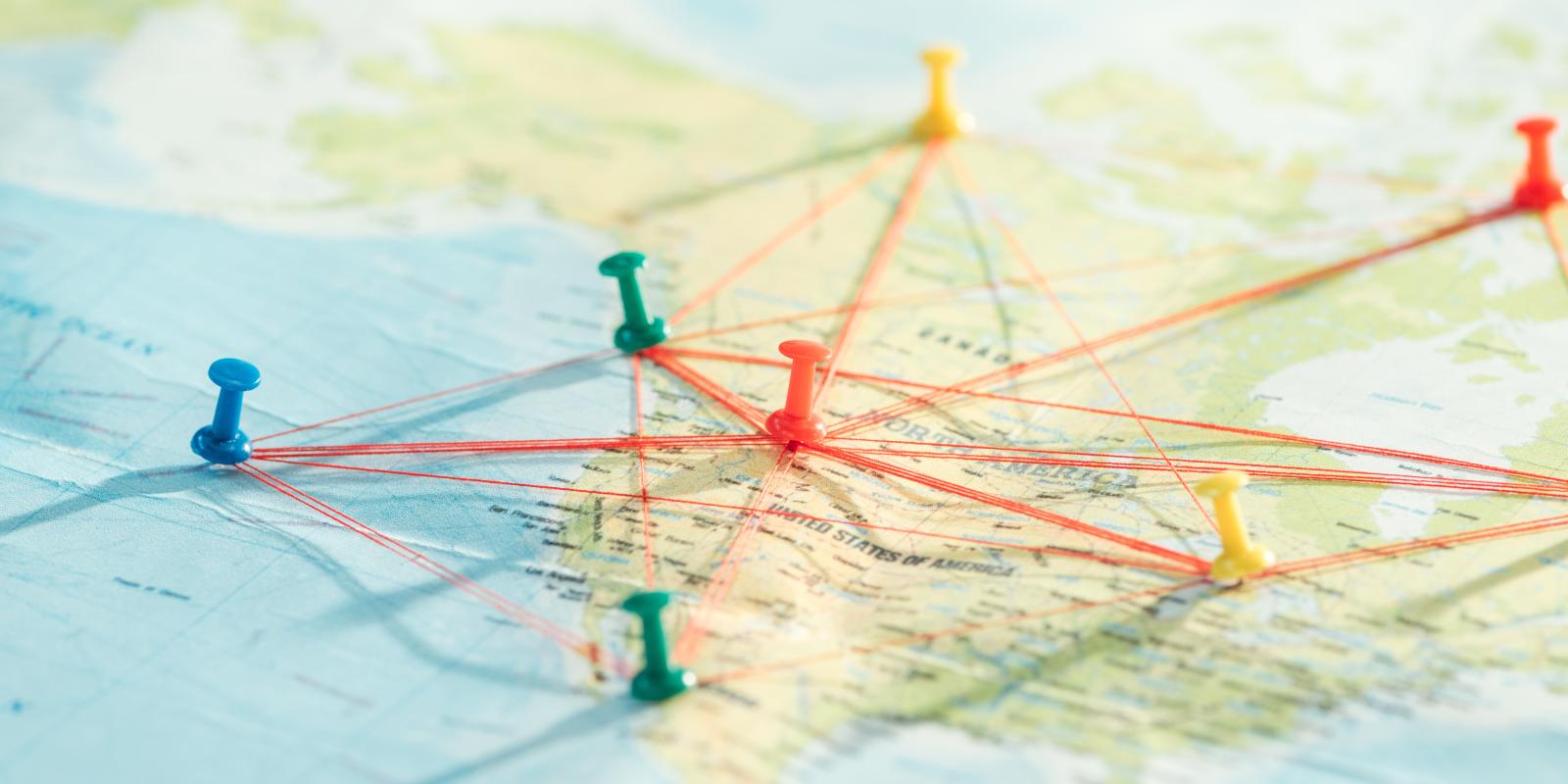 A picture of a paper map with multiple pins placed on it,