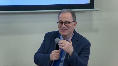 A male is talking into a microphone and smiling