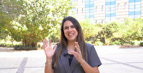 A female is talking and smiling. She is in a garden
