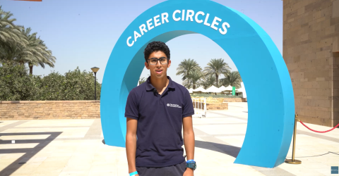 A male is standing outdoors. He is standing in front of a blue arch that says "Career Circles"